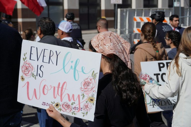 A group of people holding signs in front of a building