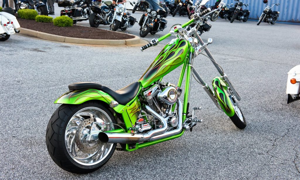 A vibrant custom green motorcycle with chrome detailing parked outdoors.