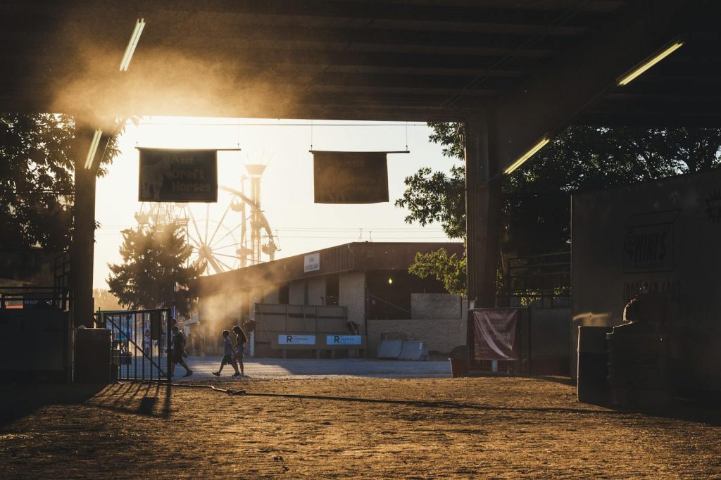 A stunning sunset view with people walking under a gate at Boise fairgrounds, featuring a Ferris wheel.
