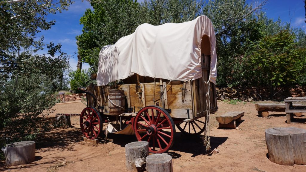 a covered wagon sitting in the middle of a dirt field