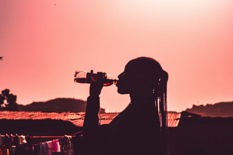 a person sitting in a chair drinking from a bottle