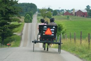 photo of two person riding on black carriage running on grey concrete road
