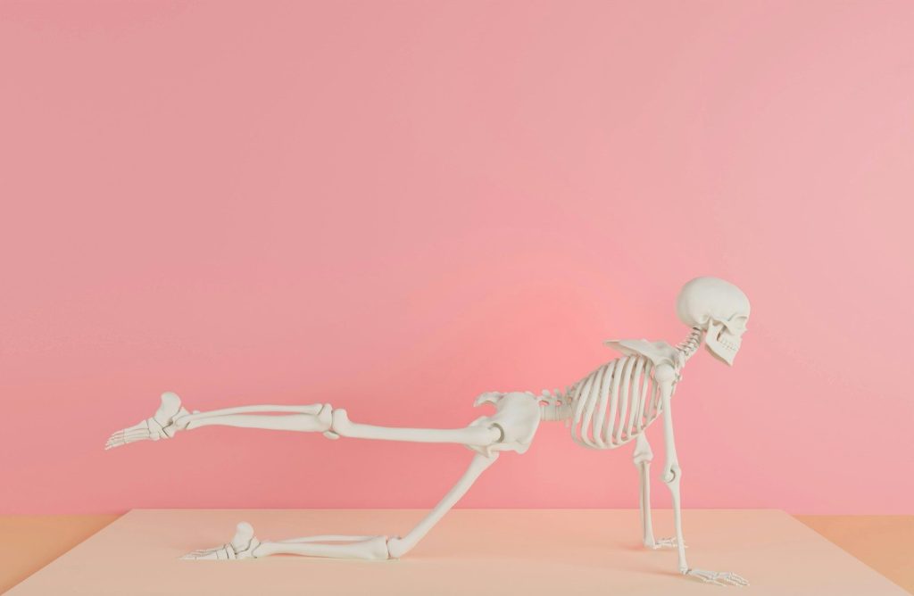 a skeleton laying on its back on a pink surface