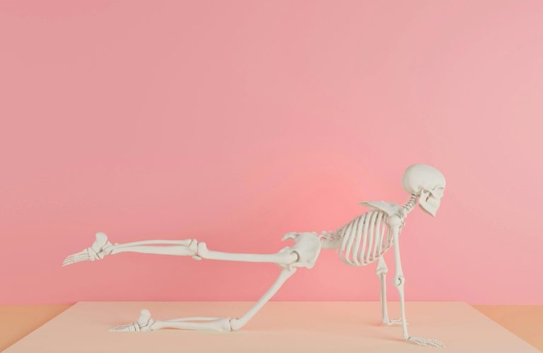 a skeleton laying on its back on a pink surface