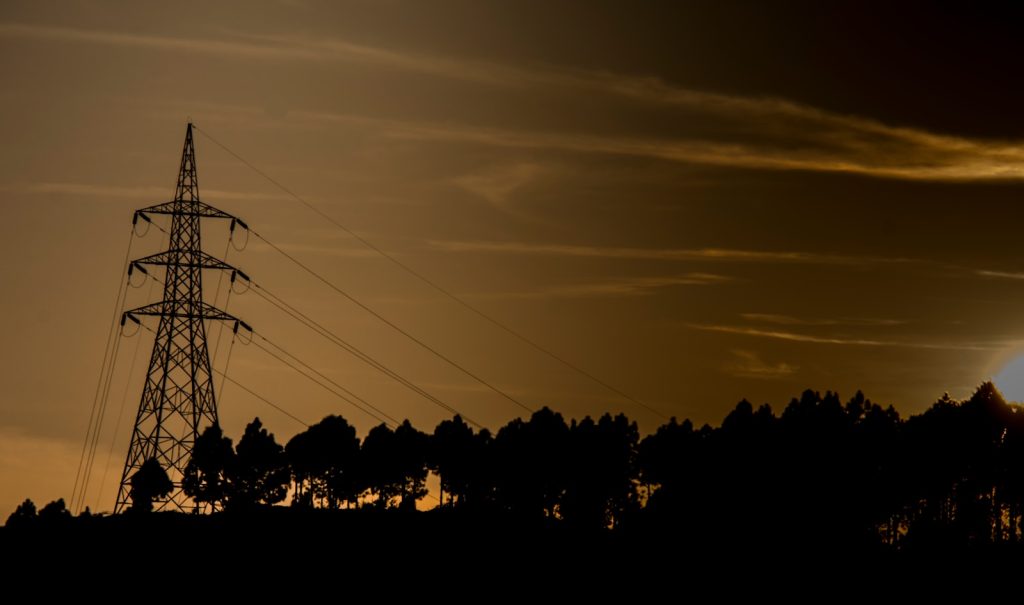 The sun is setting behind a telephone tower