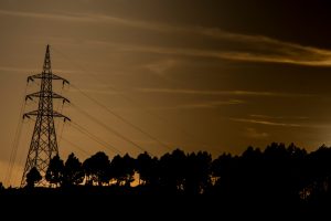 The sun is setting behind a telephone tower